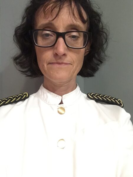 JagAnna i vit serveringsrock, med guldknappar och svart & guldfärgade klaffar på axlarna.